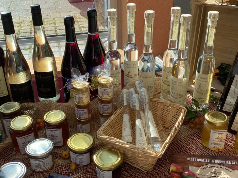 Marktstand mit frischem Obst, Gemüse und einer Person im Hintergrund.