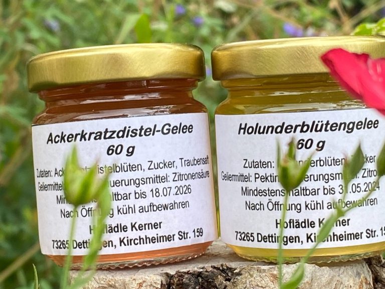 Zwei Gläser mit Gelee, eines aus Holunderblüten, das andere aus Ackerkratzdisteln.