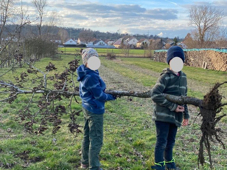 Zwei Jungen stehen auf einem Feld und halten einen Baumstamm.